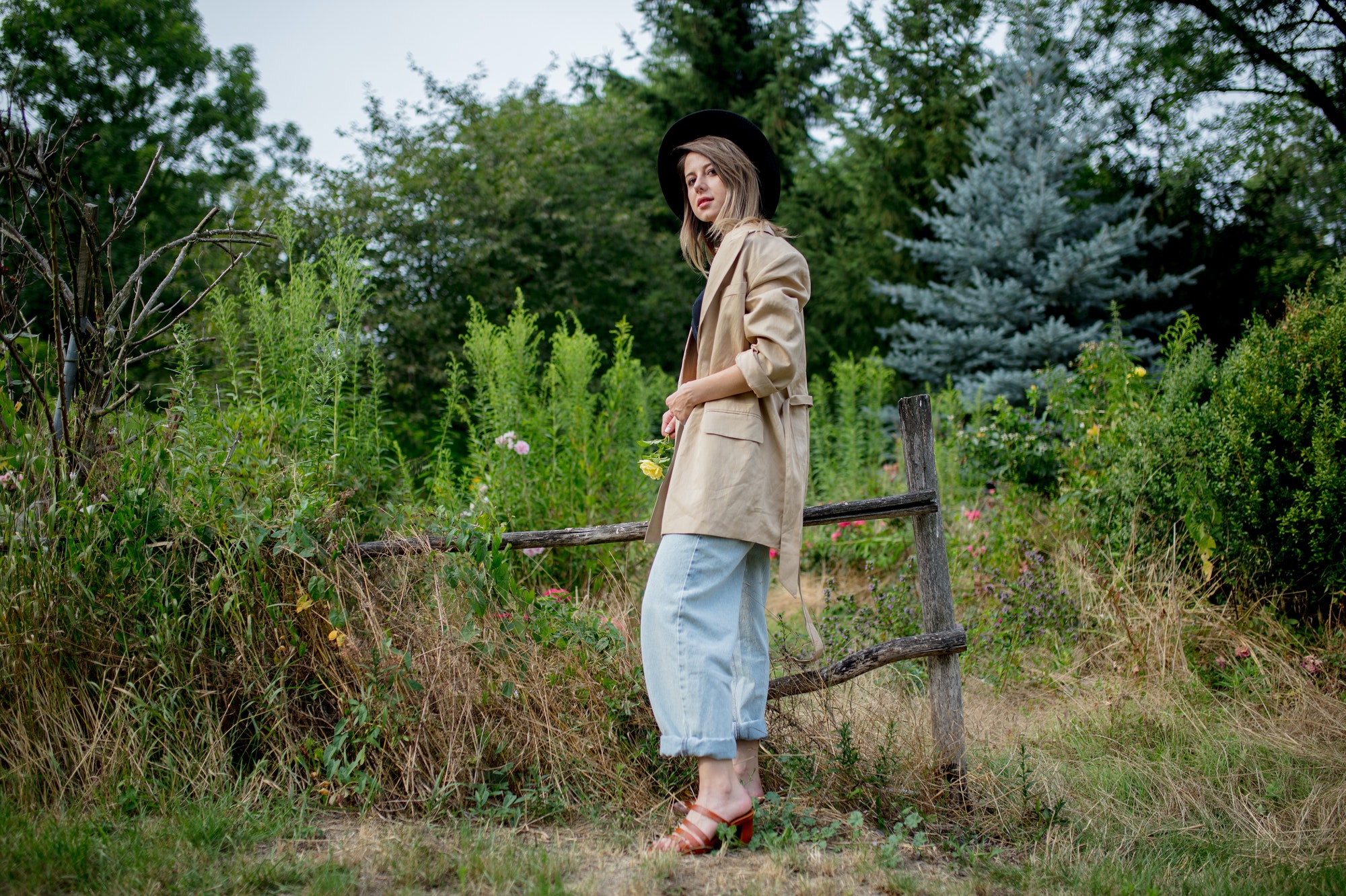 woman in hat and jacket in old countryside garden