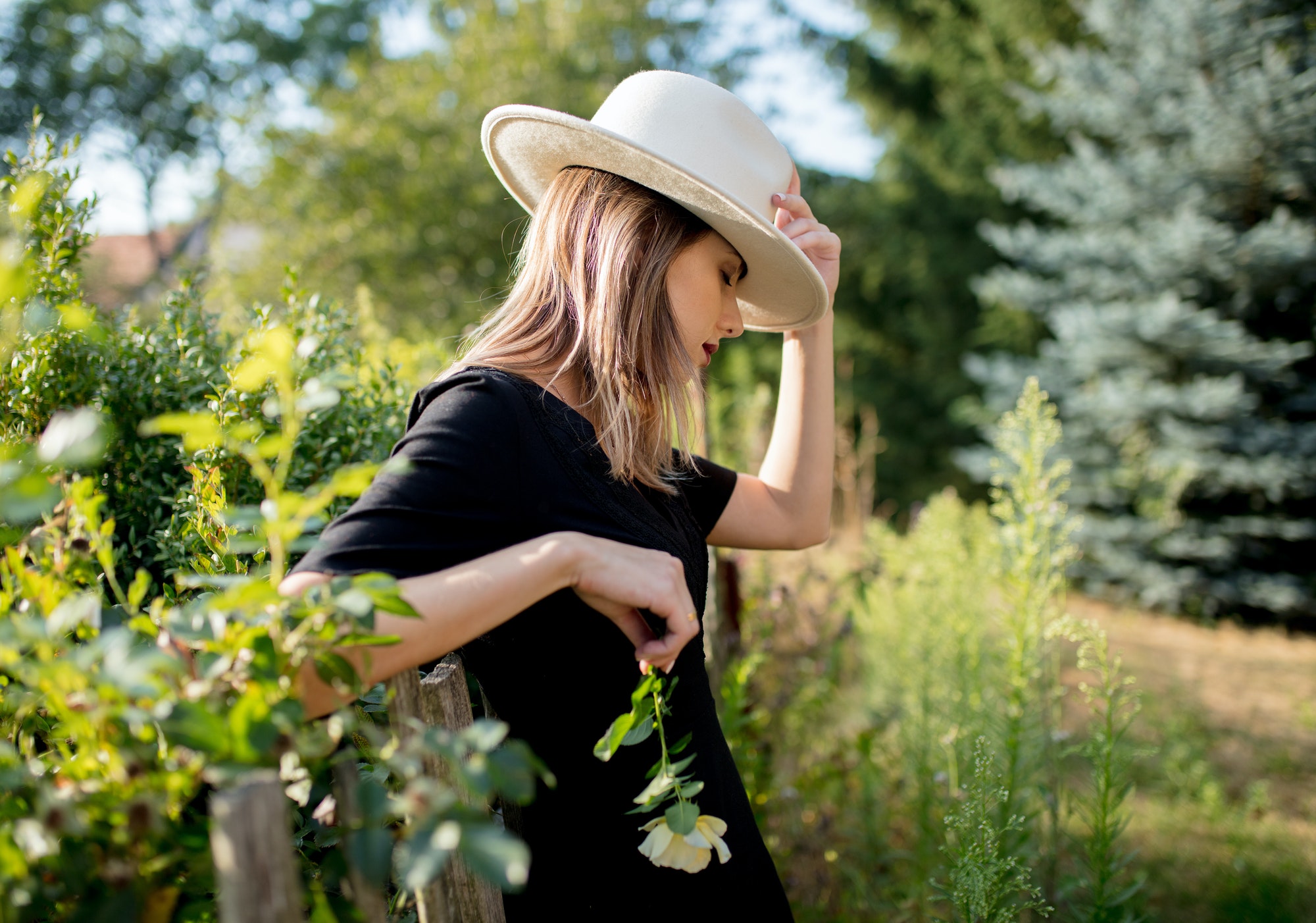 woman in hat in a summertime countryside garden